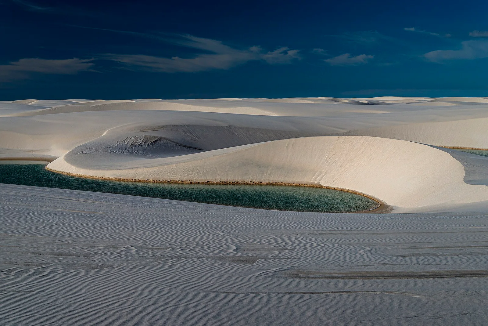 Dunas claras e lagoa no Parque Nacional dos Lençóis Maranhenses.