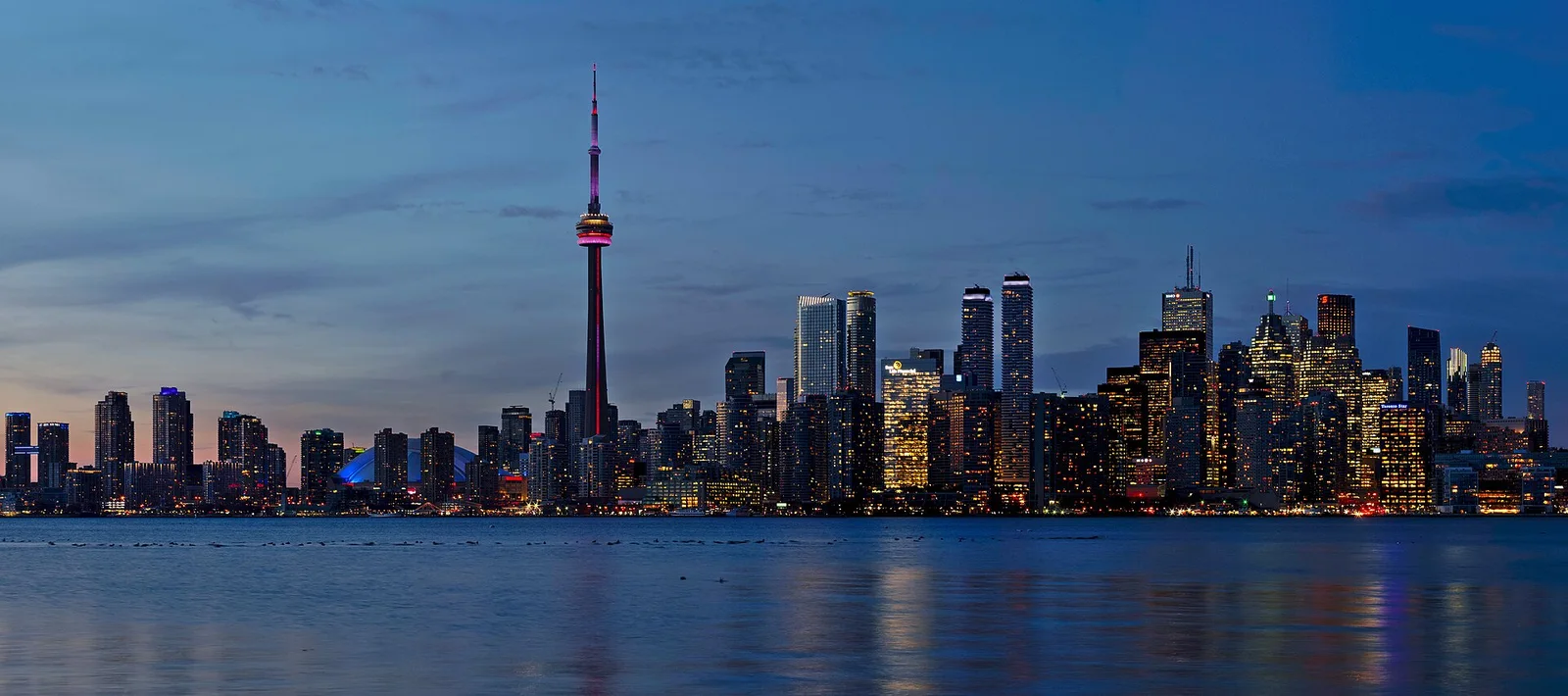 Vista do horizonte de Toronto ao entardecer, com a CN Tower junto à água.
