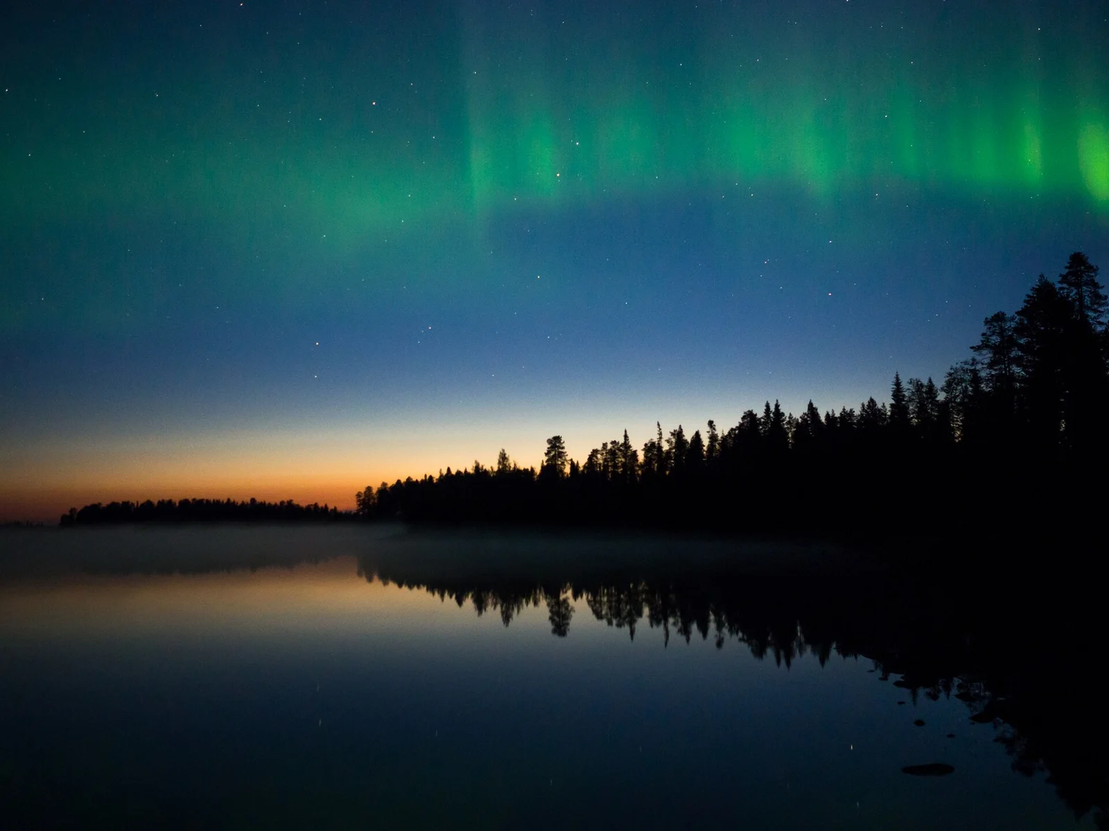 Aurora boreal verde sobre um lago em Suomussalmi, na Finlândia.