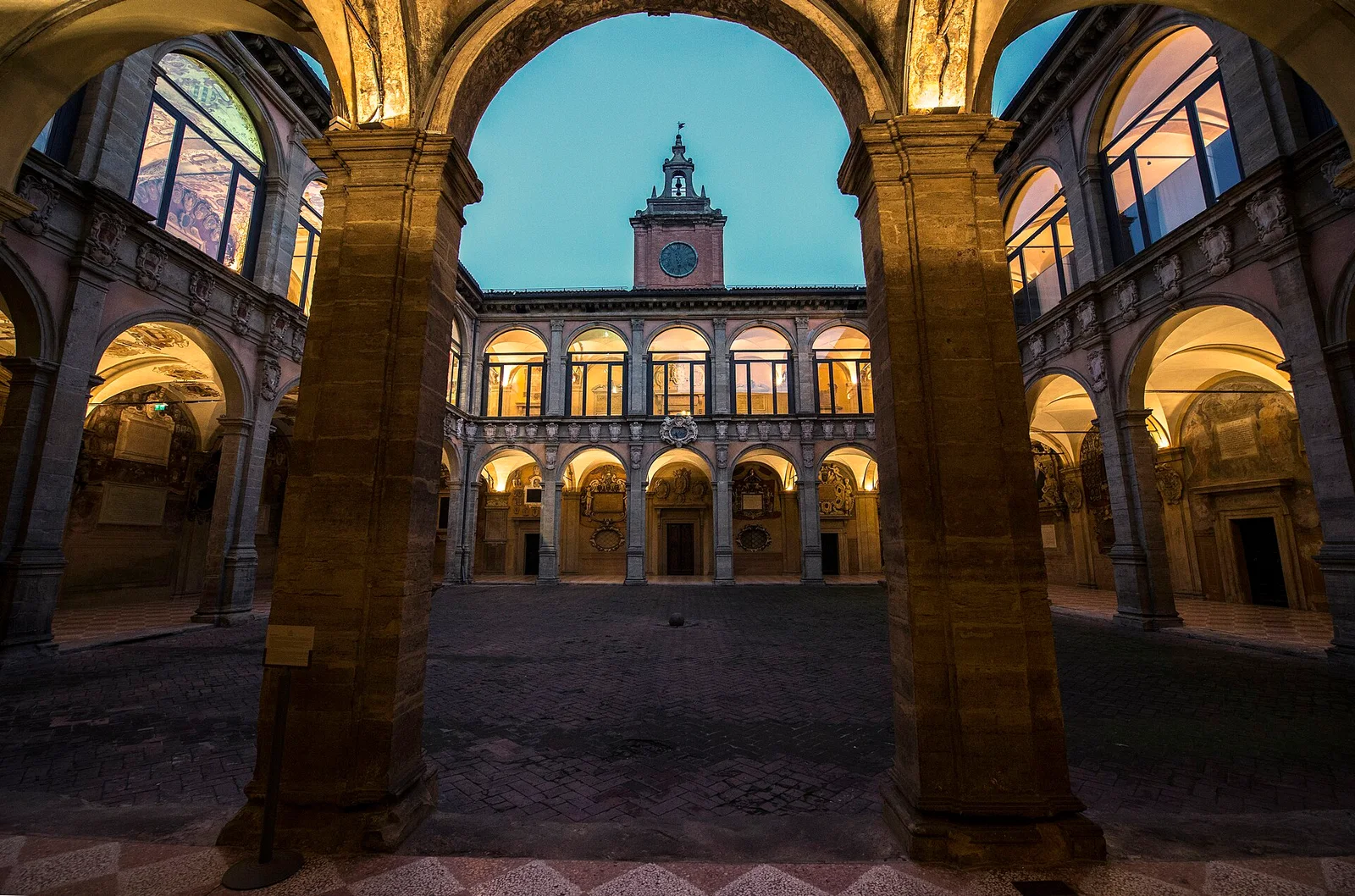 Pátio do Archiginnasio de Bolonha iluminado ao anoitecer.
