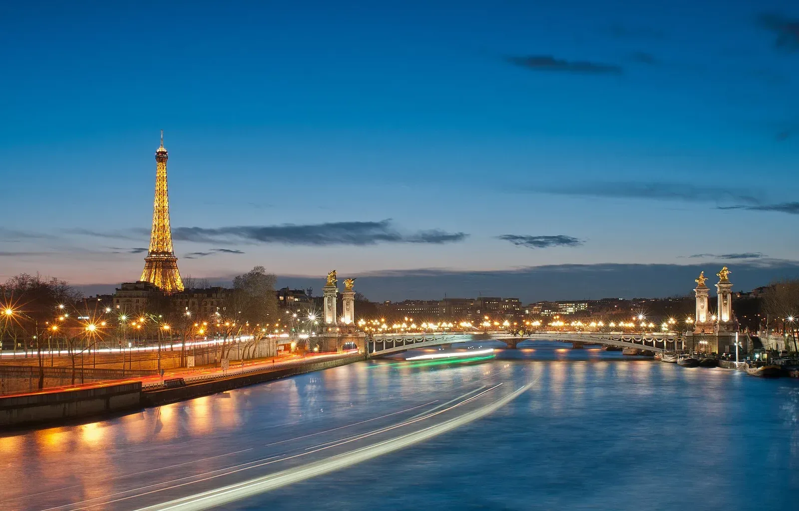 Torre Eiffel e ponte Alexandre III iluminadas junto ao rio Sena, em Paris.
